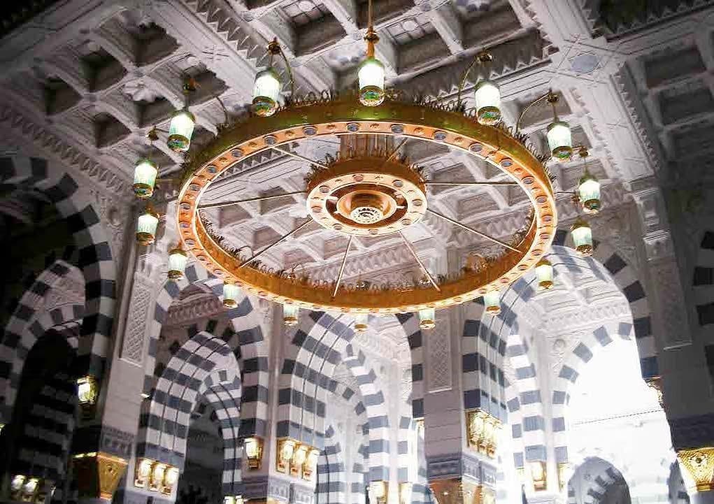 Golden chandelier hanging inside the Prophet's Mosque in Medina, highlighting intricate Islamic architecture and arched ceilings