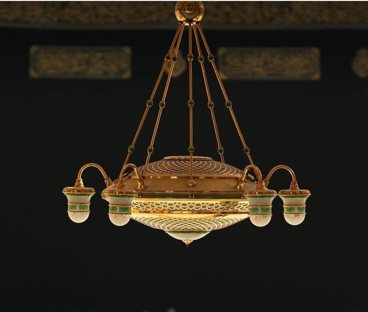 Ceiling light detail of the Holy Mosque in Makkah featuring a golden chandelier with green glass and intricate geometric patterns