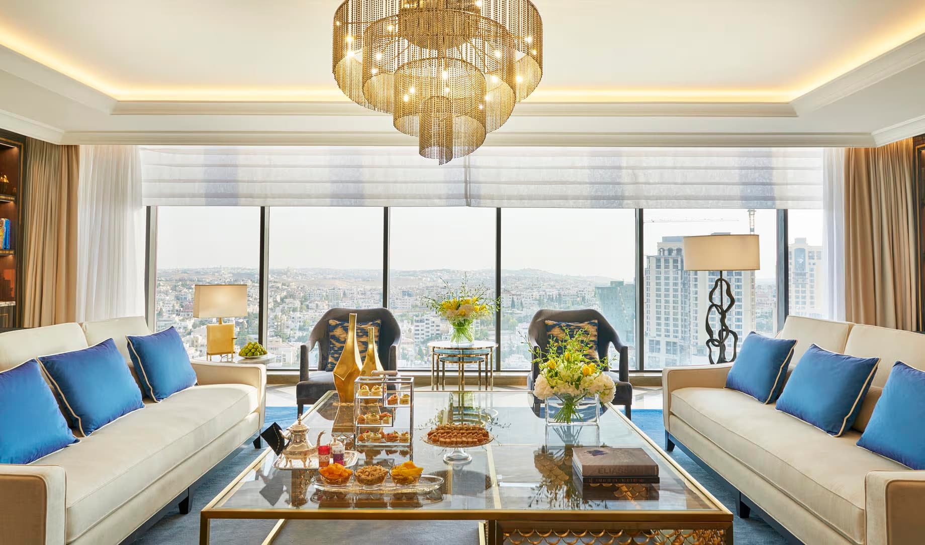 Bespoke gold chandelier in a modern hotel suite with city views at the Fairmont Amman