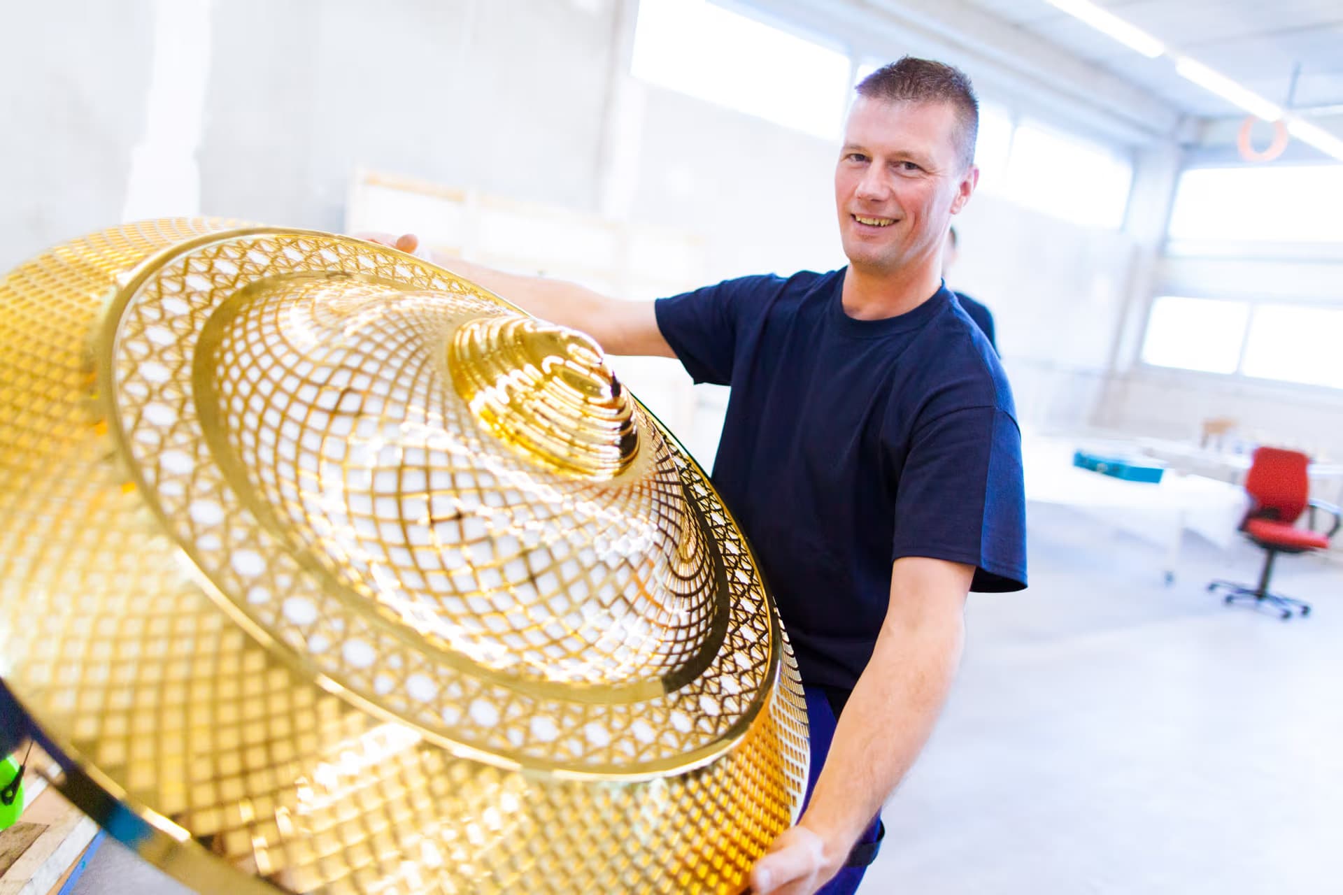 Craftsman with golden handcrafted chandelier in workshop for mosque lighting