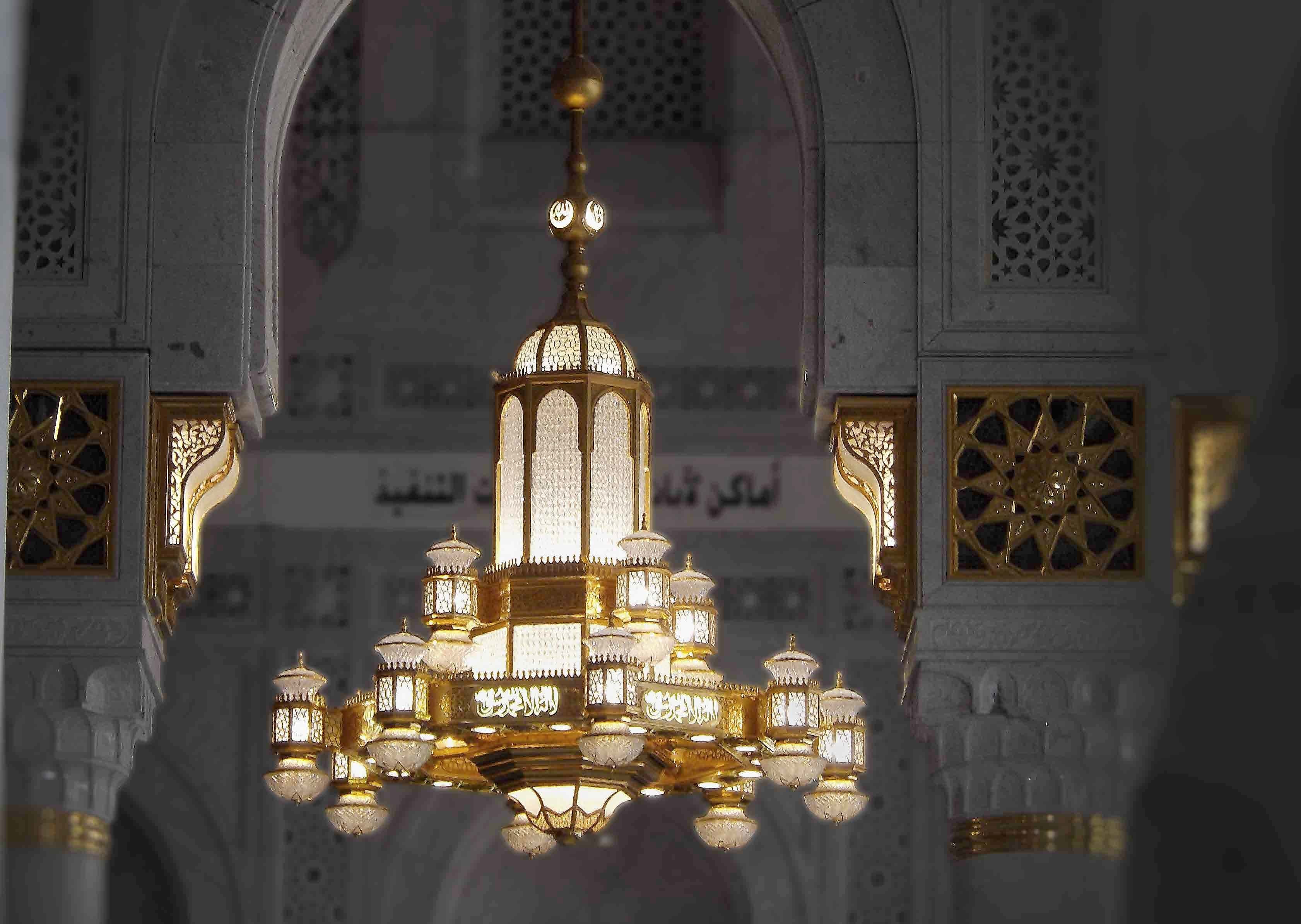 Interior view of the Holy Mosque in Makkah with grand golden chandeliers, marble arches and intricate Islamic Patterns