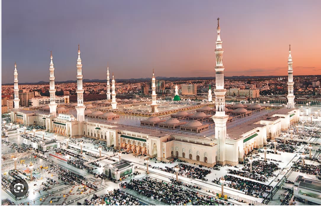 Aerial view of the Prophet's Mosque in Medina, Saudi Arabia, showing the grand minarets and courtyard at sunset