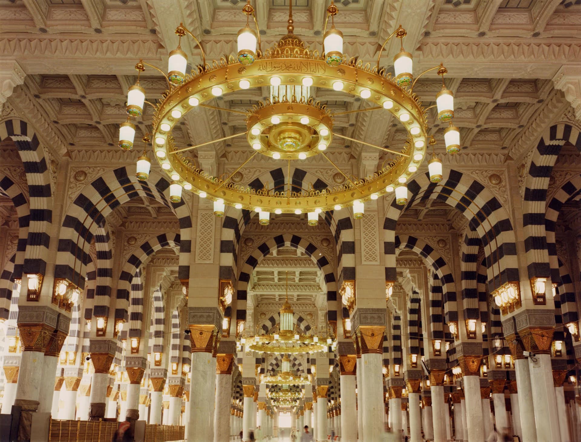 Ornate interior of the Prophet’s Mosque in Medina showing golden chandeliers and decorative arches